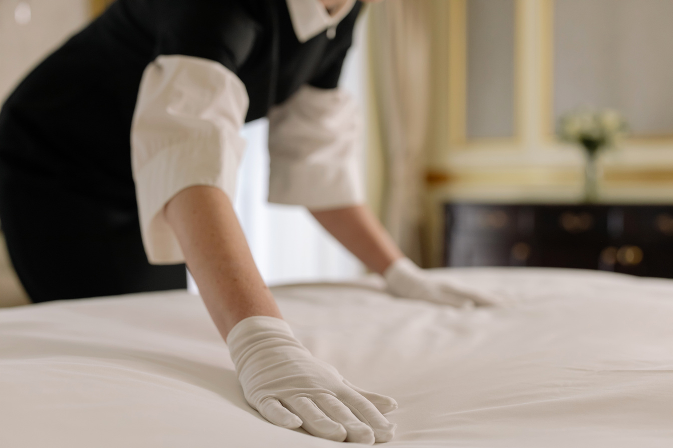 Woman Fixing the Linen of a Bed